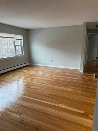 a view of an empty room with window and wooden floor