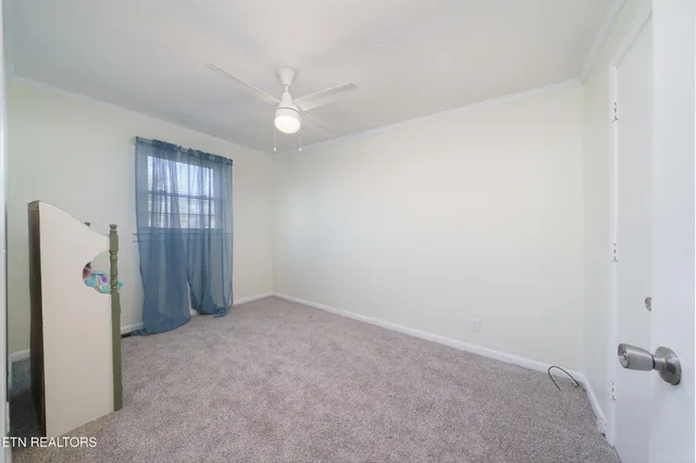 an empty room with a window and ceiling fan