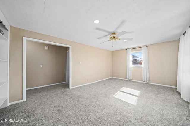 an empty room with fan and windows