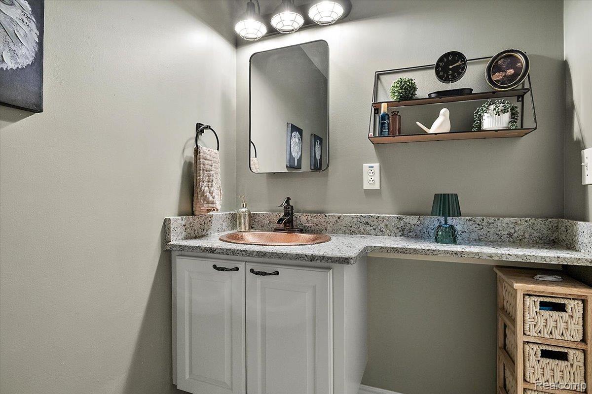 4219 Gardner Road Metamora, MI 48455 - Photo 37 of 84 Bathroom vanity featuring a copper-toned basin, speckled countertop, white cabinetry with dark hardware, and a framed mirror under a three-bulb light fixture