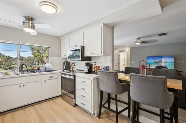 a kitchen with stainless steel appliances granite countertop a stove a sink dishwasher a dining table and chairs with wooden floor