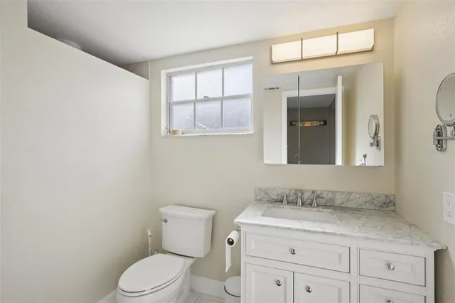 a bathroom with a granite countertop toilet sink and mirror