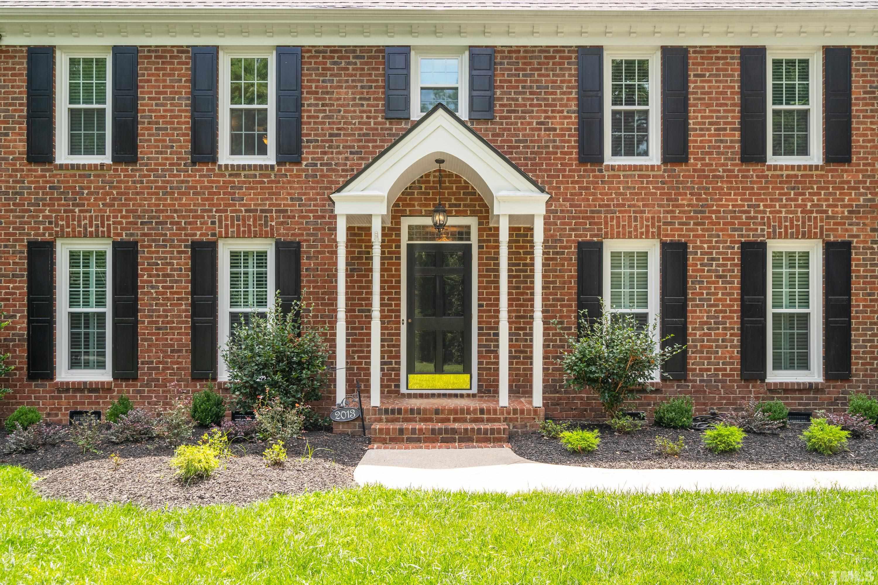 2013 Countrywood Road North Raleigh, NC 27615 - Photo 4 of 73 a view of a brick house with yard and plants