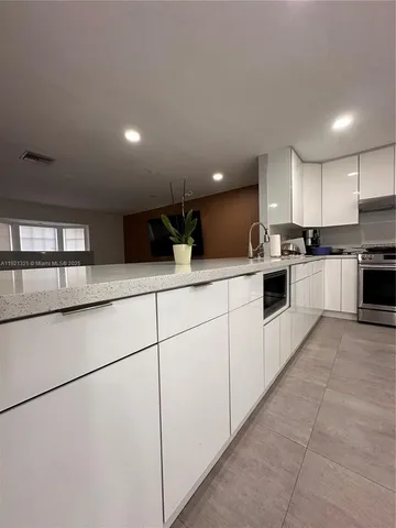 a kitchen with stainless steel appliances kitchen island granite countertop a sink a stove top oven and white cabinets