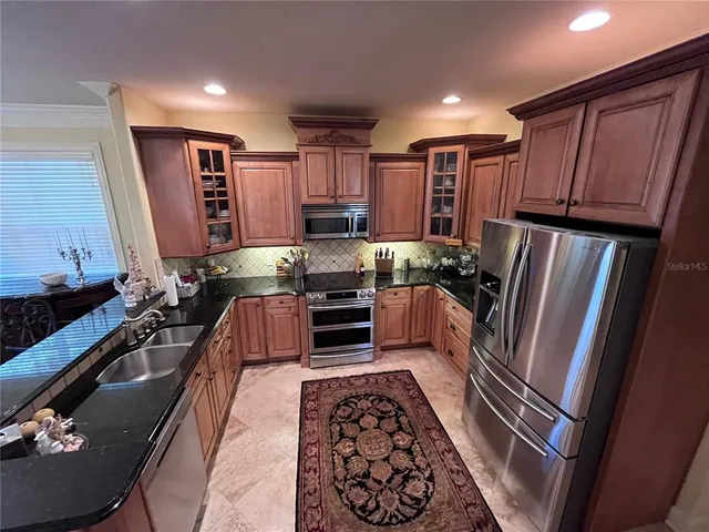 a kitchen with stainless steel appliances granite countertop a refrigerator stove and sink
