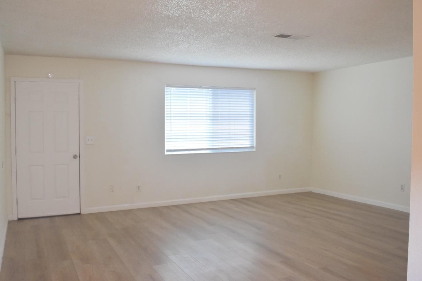 722 East Swain Road Stockton, CA 95207 - Photo 9 of 16 an empty room with wooden floor and windows