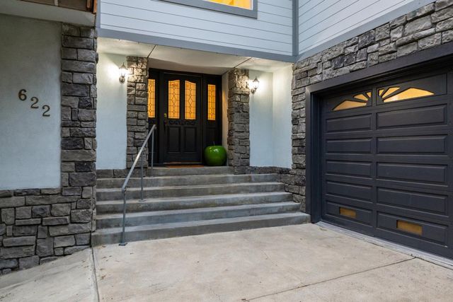 a kitchen with stainless steel appliances kitchen island granite countertop a dining table chairs and a wooden floor