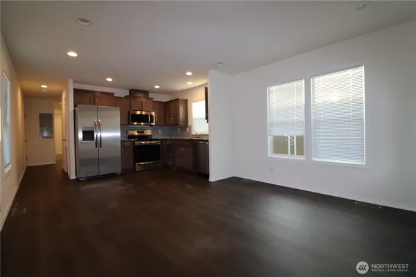 a kitchen with kitchen island granite countertop a refrigerator a sink and wooden cabinets