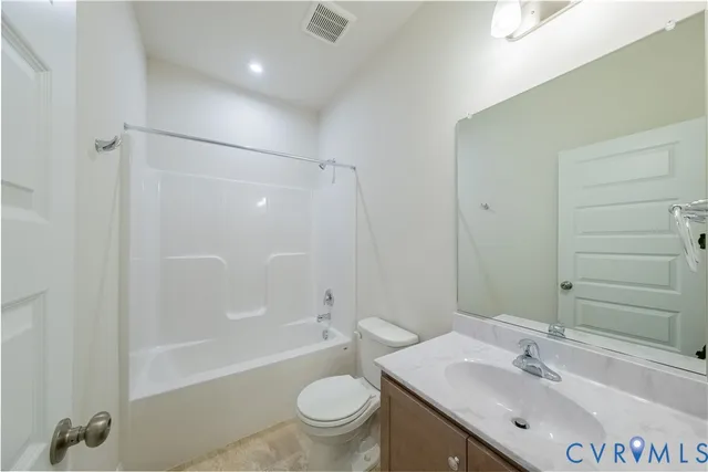 a bathroom with a bathtub shower sink vanity mirror and toilet