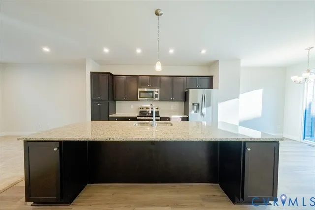 a kitchen with kitchen island granite countertop a sink a center island stainless steel appliances and a counter top space