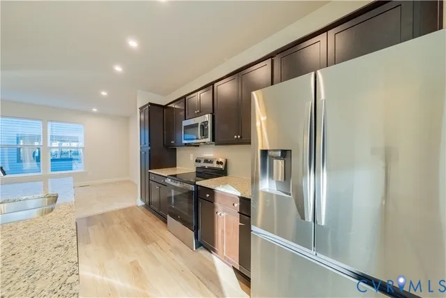 a kitchen with stainless steel appliances granite countertop a refrigerator a stove and a sink