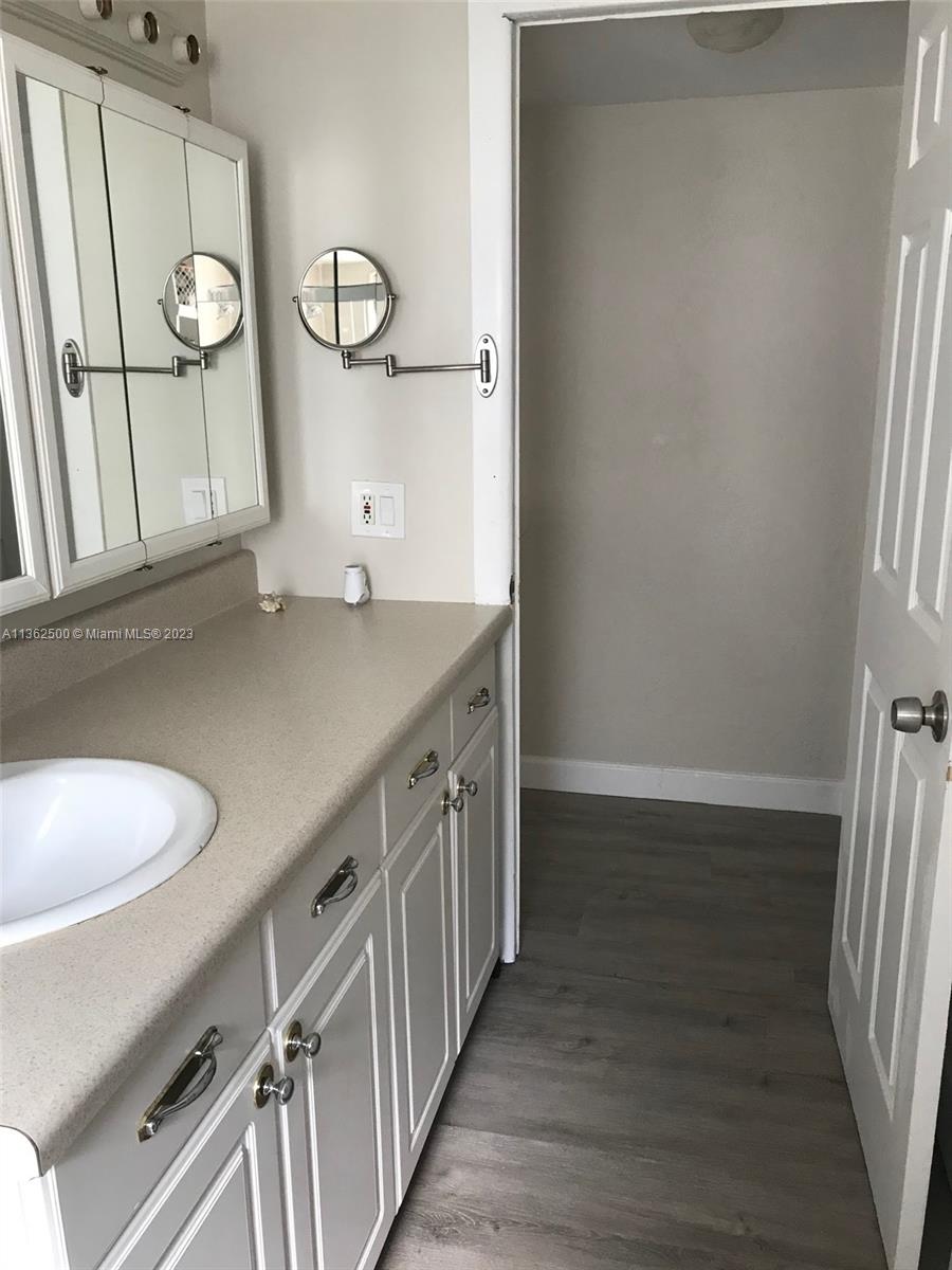 4565 Duhme Road, Unit 105 St. Petersburg, FL 33708 - Photo 14 of 19 a bathroom with a granite countertop sink a toilet a mirror and vanity
