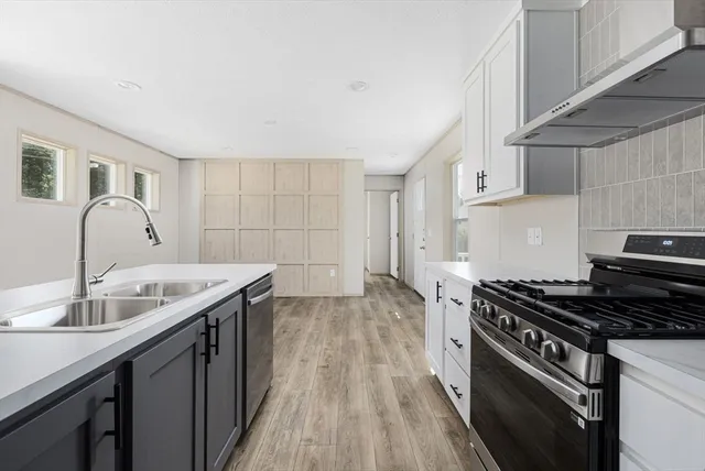 a kitchen with a sink stove top oven and cabinets