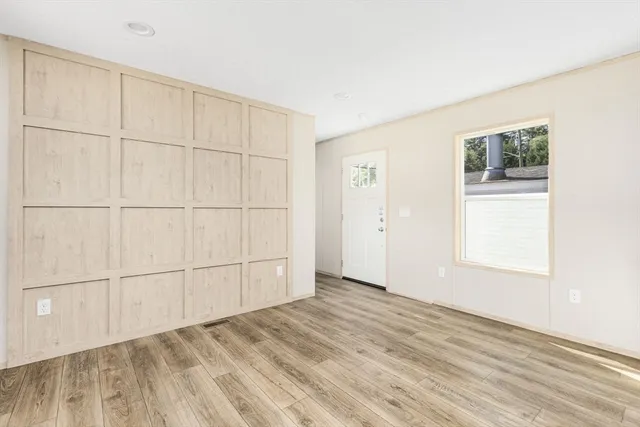 an empty room with wooden floor and windows