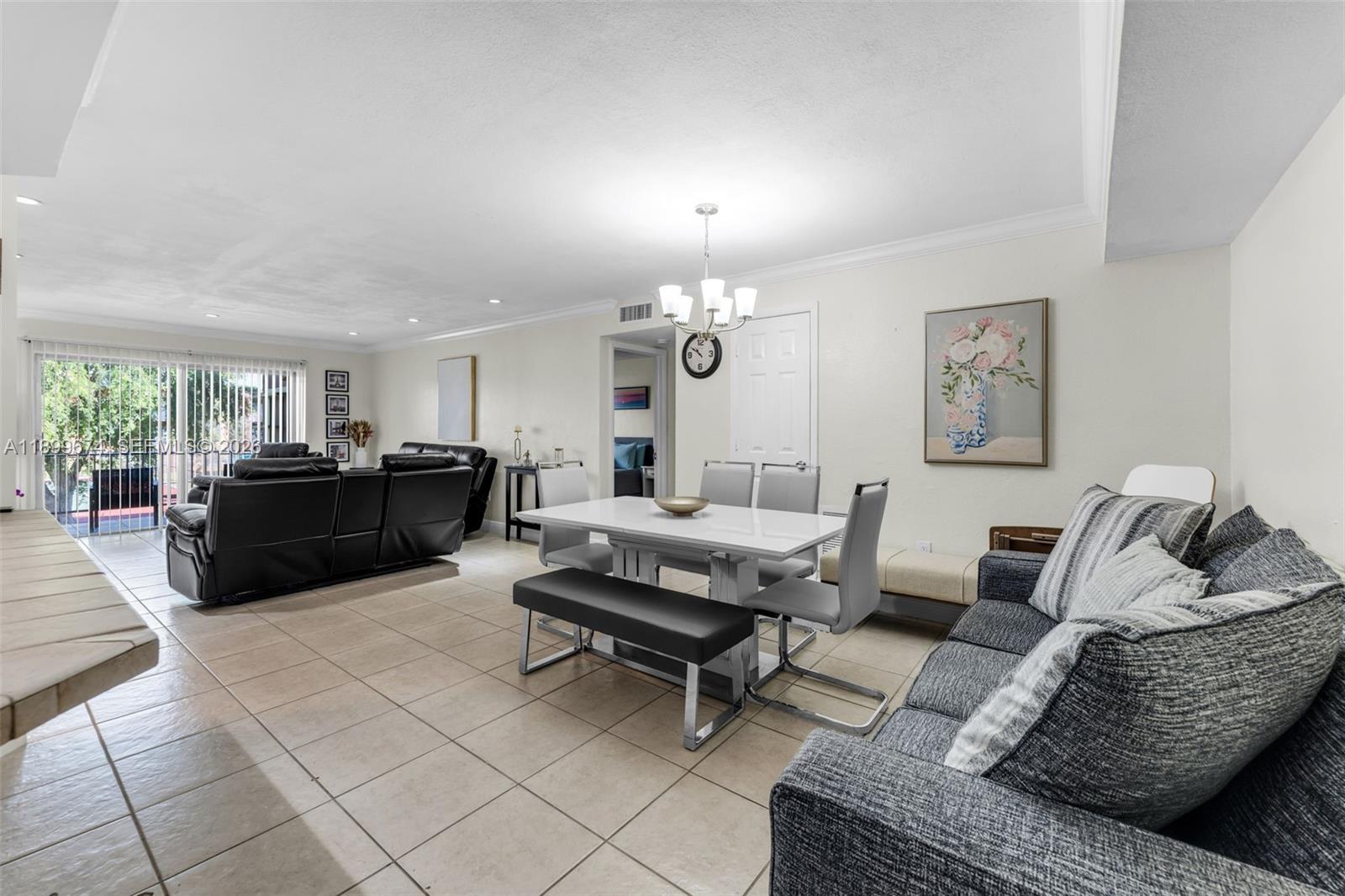 9437 Southwest 76th Street, Unit V25 Miami, FL 33173 - Photo 6 of 30 a living room with furniture a rug and a chandelier