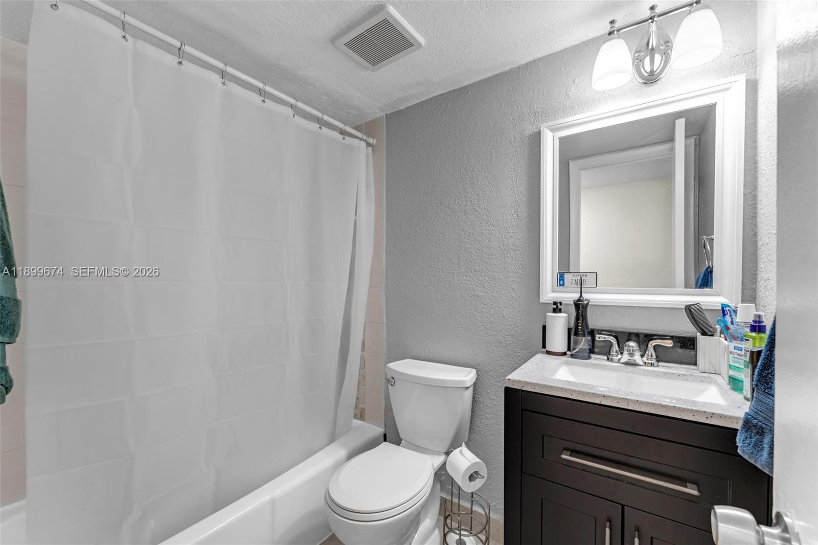 9437 Southwest 76th Street, Unit V25 Miami, FL 33173 - Photo 10 of 30 a bathroom with a toilet a sink and a mirror