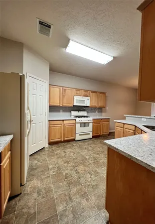 a kitchen with stainless steel appliances granite countertop a refrigerator a stove and a sink
