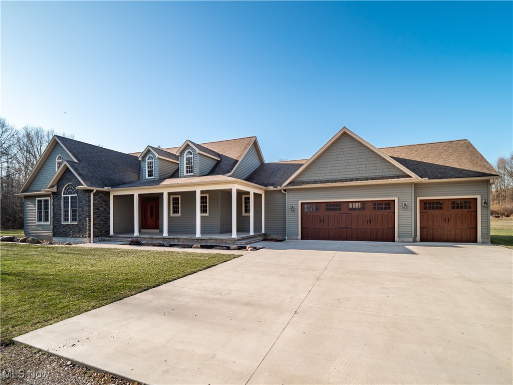 12740 Root Road Columbia Station, OH 44028 - Photo 5 of 47 View of front of home featuring a shingled roof, a front lawn, a porch, concrete driveway, and an attached garage