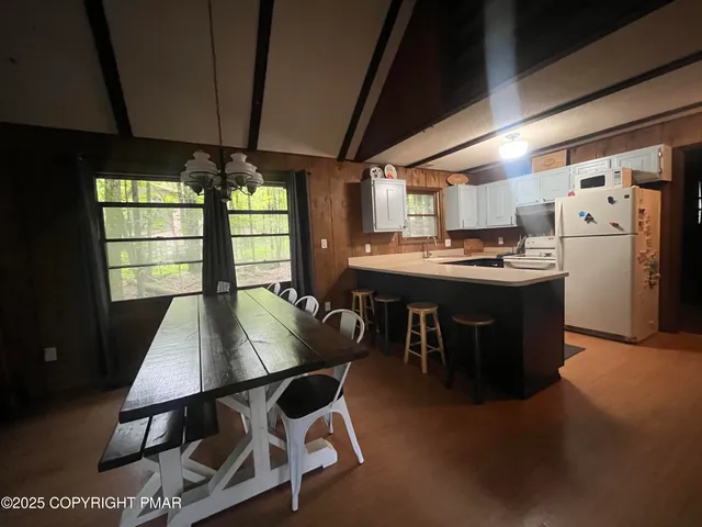 a kitchen with stainless steel appliances kitchen island a table chairs in it and wooden floors