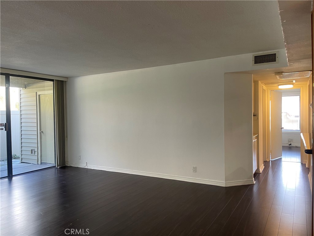 95 Country Mile Road, Unit 245 Pomona, CA 91766 - Photo 7 of 19 an empty room with wooden floor and windows with curtains