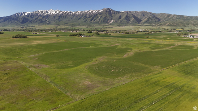 320 South 5400 West Logan, UT 84321 - Photo 3 of 42 Expansive green fields with distant snow-capped mountains and scattered residential structures