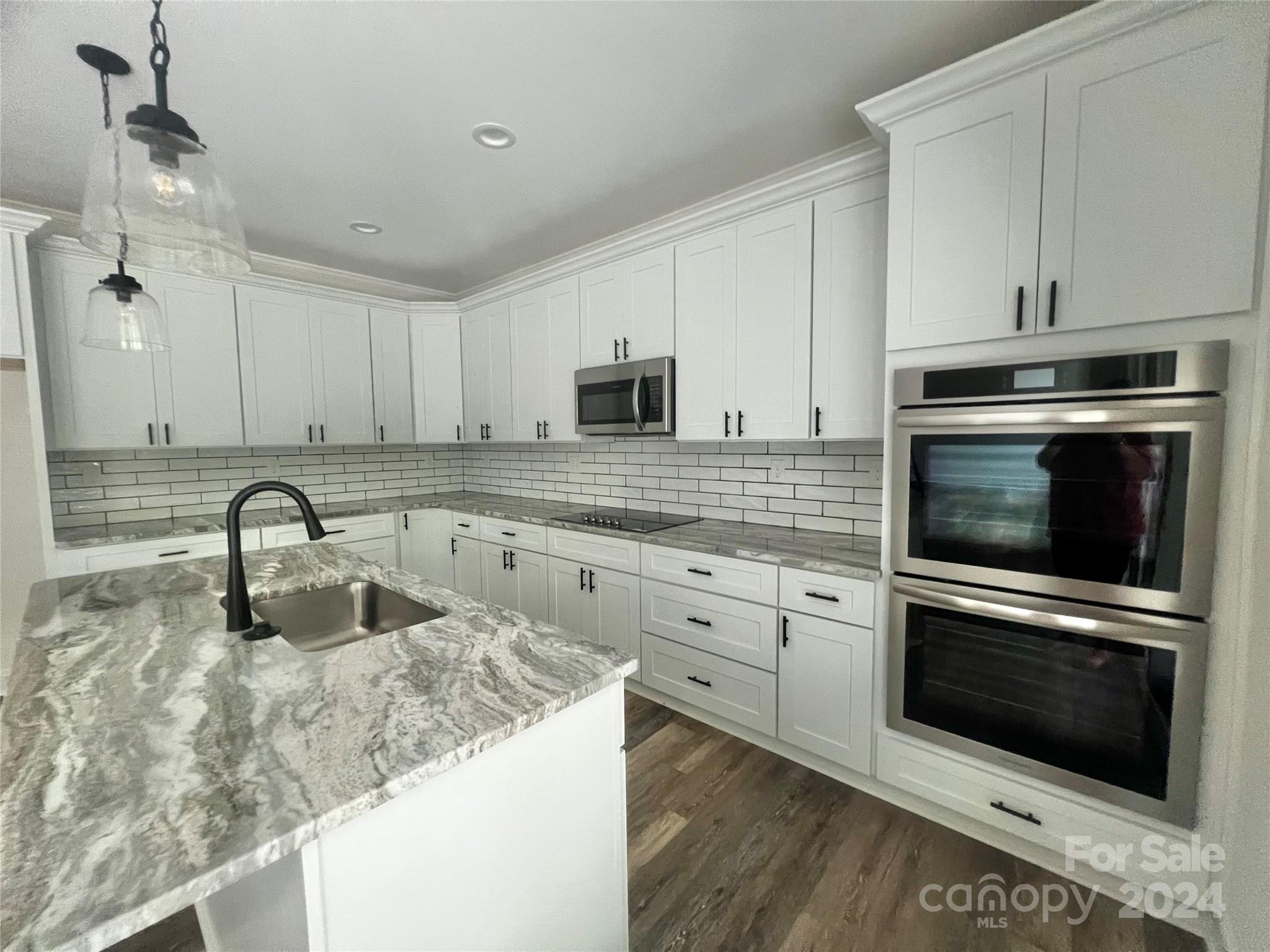 2709 Lathan Road Monroe, NC 28112 - Photo 6 of 26 a kitchen with granite countertop a sink stainless steel appliances and white cabinets