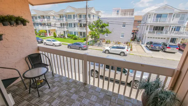 a balcony view with couple of cars parked in front of a building
