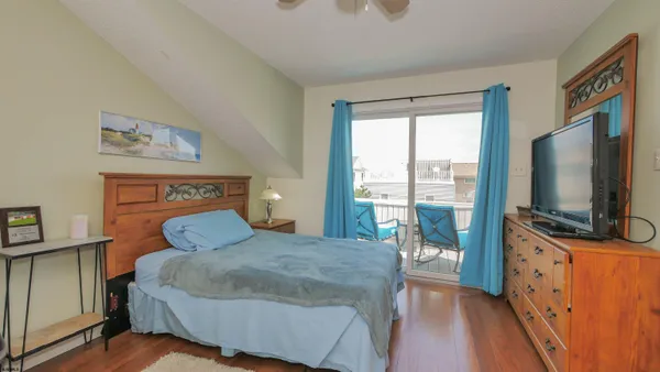 a bedroom with a large bed and a flat tv screen on dresser