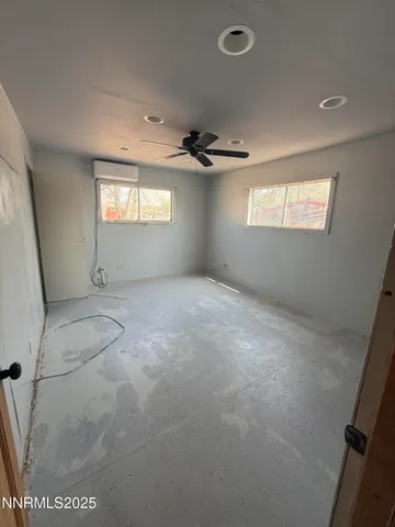 an empty room with windows and ceiling fan