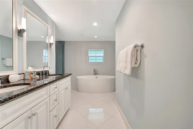a spacious bathroom with a double vanity sink a mirror and a bathtub