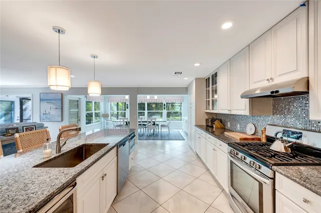 a kitchen with stainless steel appliances granite countertop a sink a stove and a wooden floors