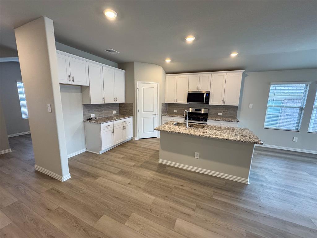 2110 Dunbar Drive Sherman, TX 75092 - Photo 4 of 22 a large kitchen with stainless steel appliances granite countertop a stove a sink and a microwave