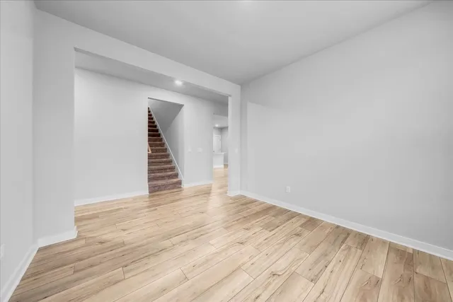 a view of an empty room with wooden floor and stairs