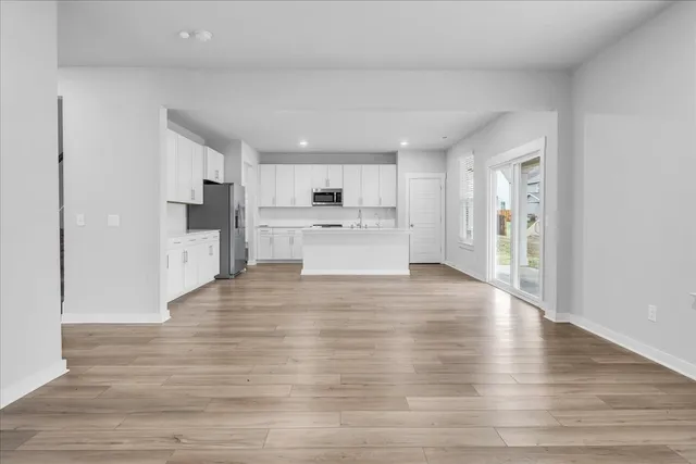 a view of a kitchen with a refrigerator a stove top oven and cabinets