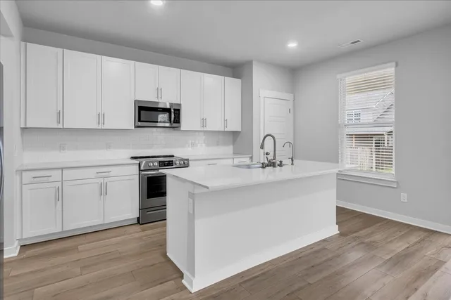 a kitchen with stainless steel appliances granite countertop a sink a stove a microwave and cabinets