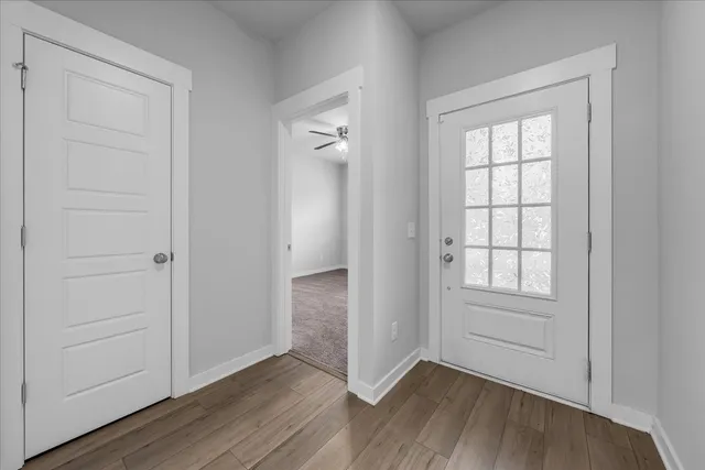an empty room with wooden floor closet and windows