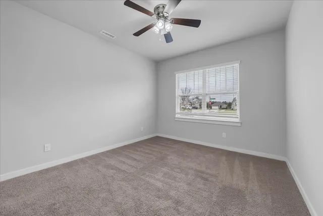 an empty room with windows and fan