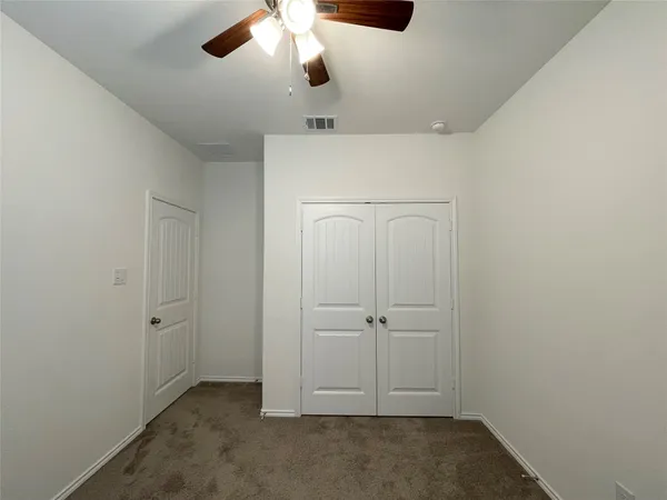 a view of an empty room with a large window with a ceiling fan