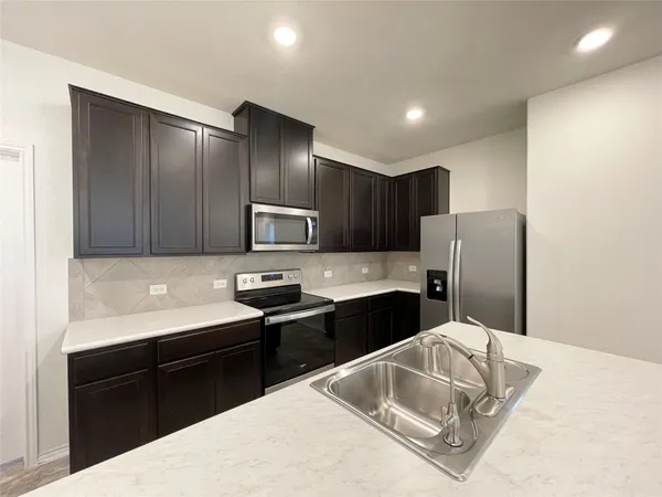 a kitchen with stainless steel appliances granite countertop a sink refrigerator and cabinets