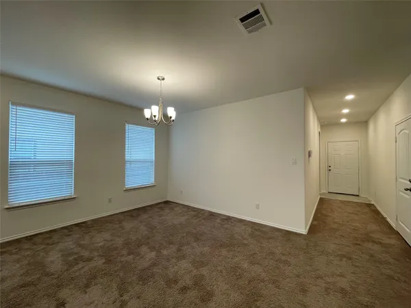 an empty room with chandelier fan and windows