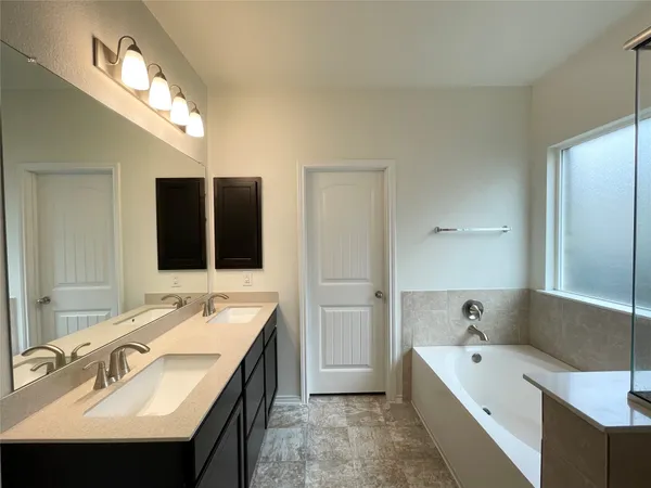 a bathroom with a double vanity sink mirror and bathtub