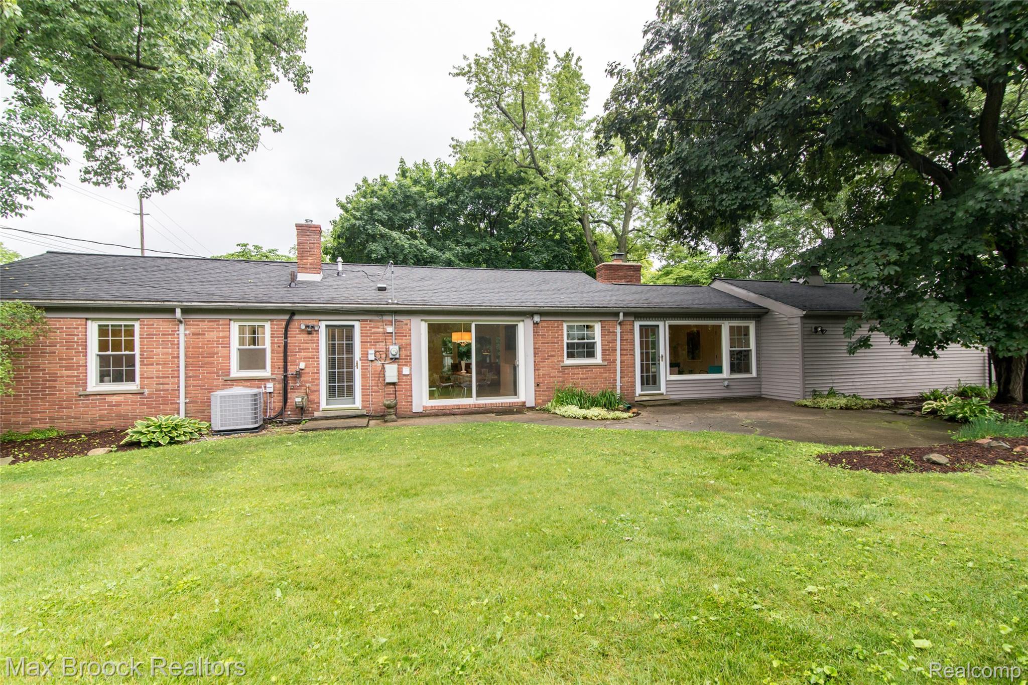 6799 East Dartmoor Road West Bloomfield, MI 48322 - Photo 32 of 36 Expansive backyard featuring a manicured lawn, brick exterior, dedicated patio space, mature trees, and multiple points of entry