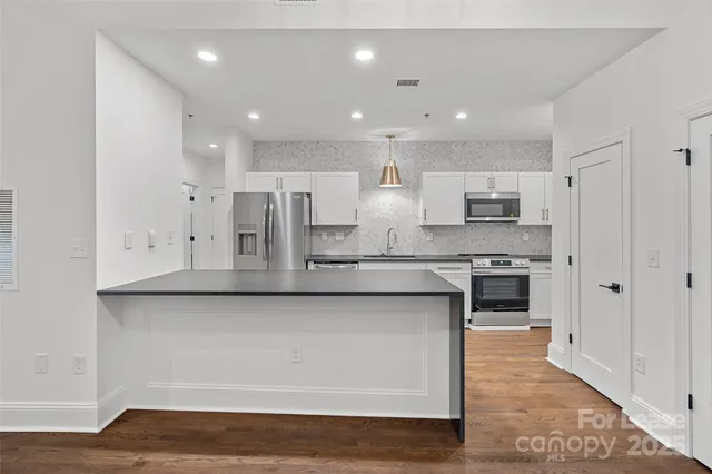 a large kitchen with granite countertop a large counter top stainless steel appliances and cabinets