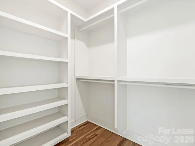 a view of an empty room with wooden floor and window