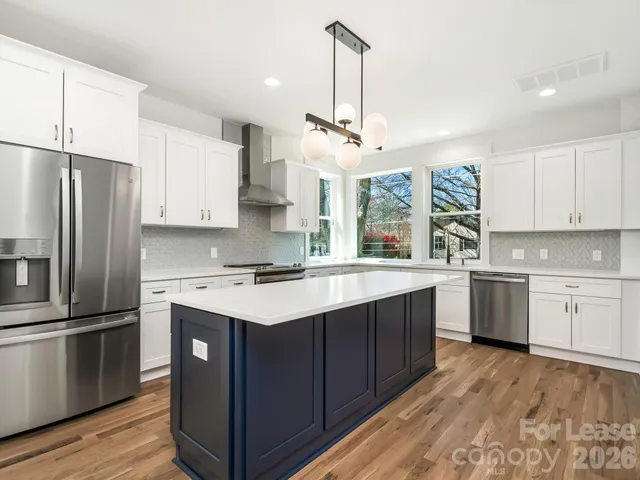 a kitchen with stainless steel appliances granite countertop white cabinets and a stove a refrigerator with white cabinets