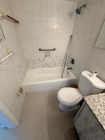a white toilet sitting next to a bath tub and a shower