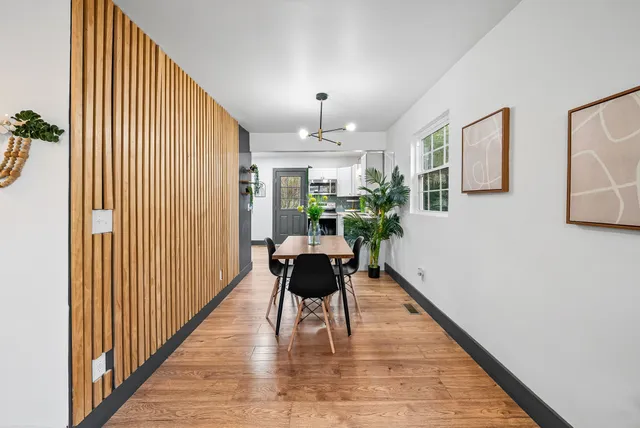 a dining room with furniture a potted plant and wooden floor