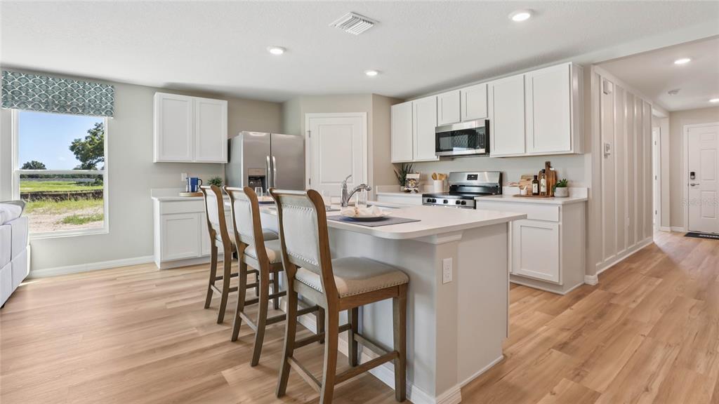 4640 Connection Road Wildwood, FL 34785 - Photo 5 of 30 a kitchen with stainless steel appliances a microwave a sink a stove a table and chairs