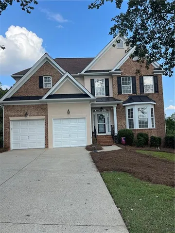 a front view of a house with a garden and trees