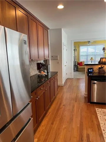 a kitchen with stainless steel appliances a refrigerator a sink a stove and wooden floor